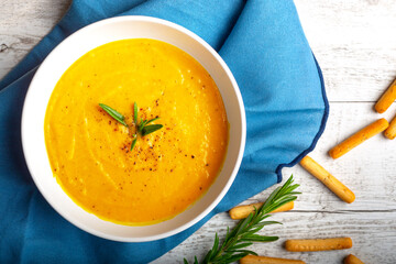 Pumpkin soup with linen napkin on light background.