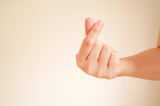 woman hand with mini heart or finger hearts gesture by crisscrossing index finger with thumb , used to convey one's love to their loved ones ,with copy space