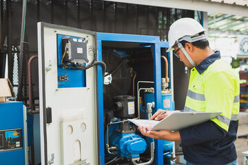 The factory's electrical engineers wear green protective clothing and plastic caps. Use laptops and tablets to check the quality of industrial equipment.
