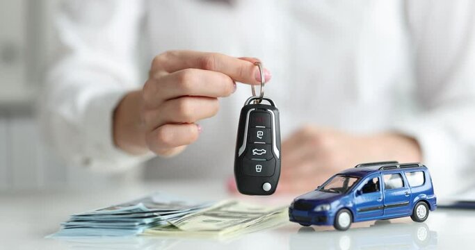 Dealer holding car keys against background of toy car and money closeup 4k movie