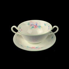 antique crockery for table setting. vintage porcelain soup cup with flower pattern on black isolated background