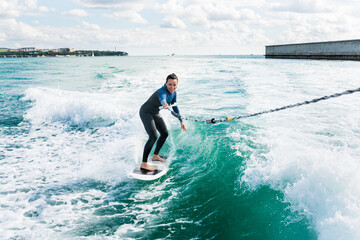 Watersport concept. Young athletic woman learning wakesurfing and perfecting tricks. Female in...