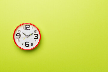 Red alarm clock on color background, top view
