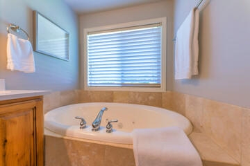 Alcove bathtub with tiles surround near the window with blinds