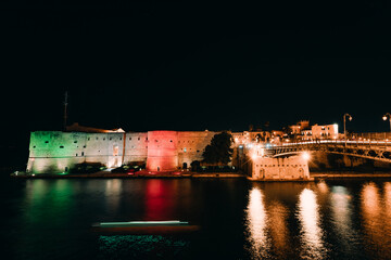 Long exposure at night of the Aragonese Castle of Taranto illuminated with the tricolor flag