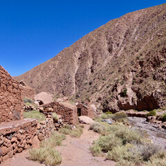 Ruin stone houses in desert mountain landscape with salt rock canyon in Atacama, with blue sky
