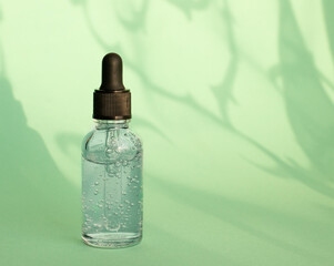 Cosmetic bottle with serum, hyaluronic acid for skin care on the background of shadows. Beauty and body care product concept