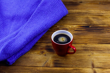 Cosy knitted blue sweater and cup of coffee on wooden table. Winter cozy concept