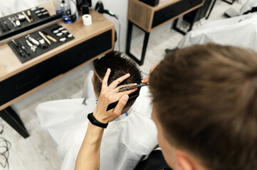barber in the process of cutting a client in a barbershop. haircut with scissors in a beauty salon. master.