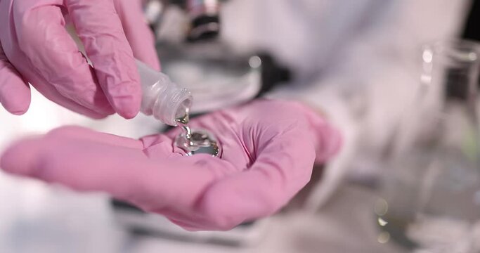 Student pours liquid mercury on gloved hand closeup