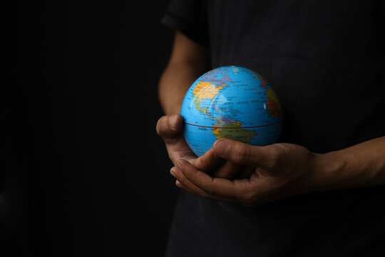 High angle view of hands holding a globe on a black background. Earth day concept with low key tone photo