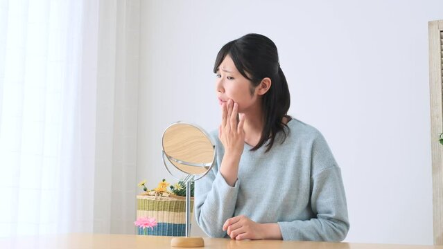 美容　鏡を見る女性　悩む