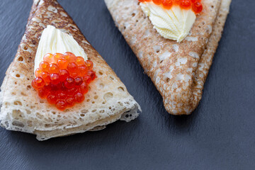 Pancake with red caviar and butter on a dark background.  Maslenitsa holiday, pancakes week. traditional slavic festival meal.