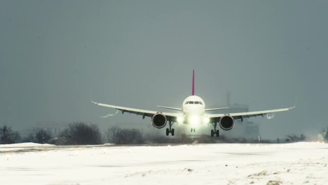 Passenger plane lands on the runway in bad weather in winter at the airport, wheels touch the ground with snow top slow motion video