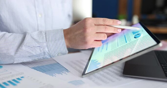 Businesswoman studying business analytics in charts on tablet closeup
