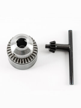 Metal drill chuck with a key on a white background.