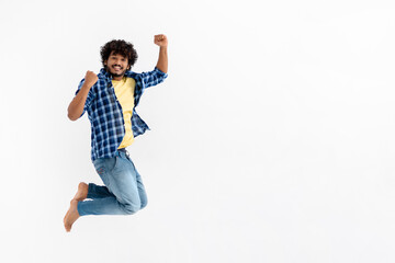 Cheerful Indian young man fun jumping on white background with copy space. Victory, celebrate triumph