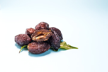 Dried dates and green leaves on a light blue background close-up.