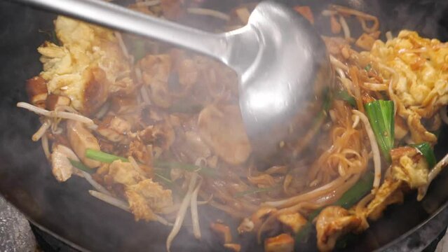 Vertical video: close up of moving wok with a Pad Thai
