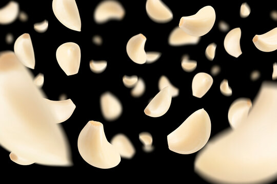 Set of peeled garlic cloves falling on a black background with selective focus. Garlic, isolated on a black background, flies down, casting a shadow.