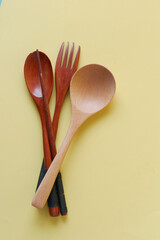 wooden cutlery forks on light yellow background 