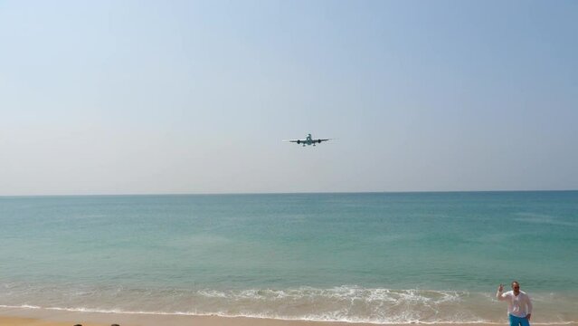 Airplane over the sea, unrecognized people on the beach