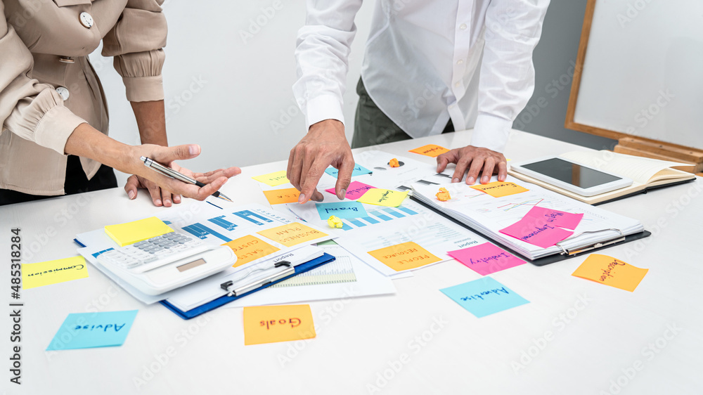 Poster Two business people pointing keyword in post it notes on the table during brainstorming about new business project