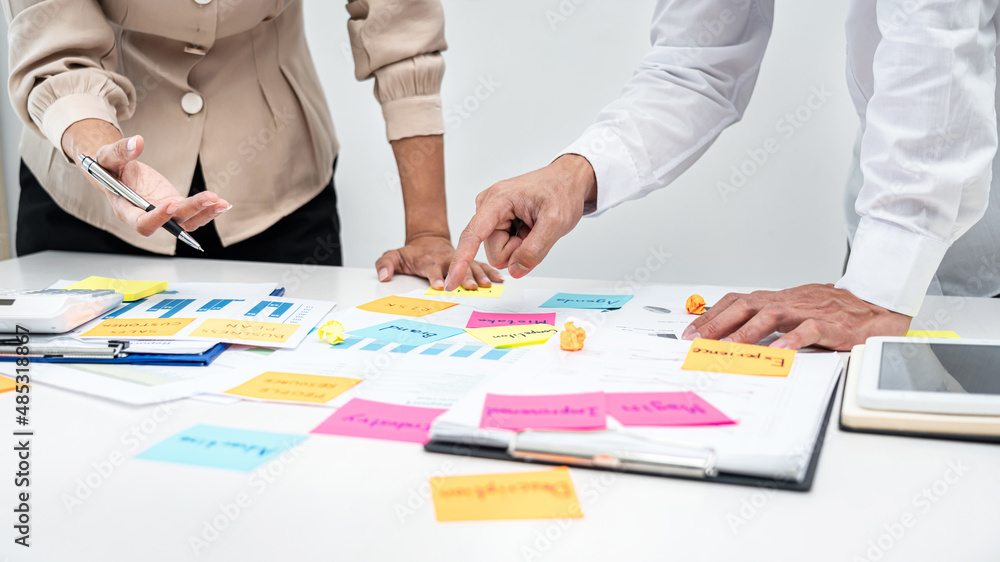 Poster Two business people pointing keyword in post it notes on the table during brainstorming about new business project