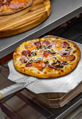 chef baker making pizza at kitchen. Put on landing shovel and send it to the oven.