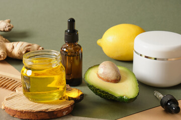 jar with oil, sliced avocado, avocado seed and two amber glass dropper bottles on a wooden stand