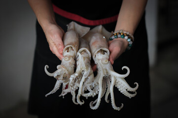 woman holding fresh squid in hand, Seafood vendor , fresh squid.