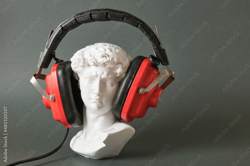 Wall mural fake bust of david with retro headphones on dark green background