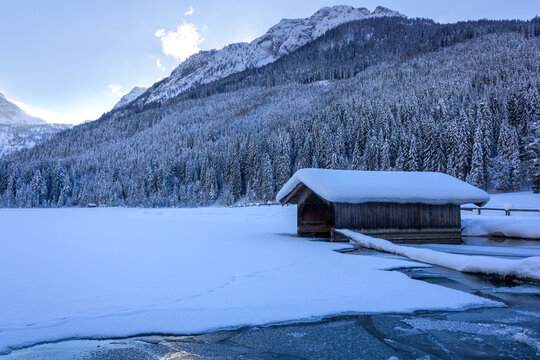 Lakeside boathouse covered with snow during wintertime with the "Maureck" mountain peak in the background (Jägersee, Kleinarl, Austria)