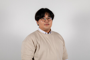 Portrait of a serious chubby young asian man in glasses on a white background