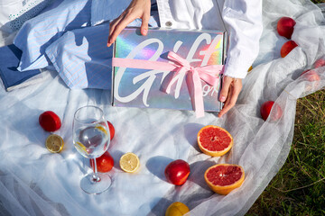 picnic in nature with fruits and white wine. girl makes a surprise