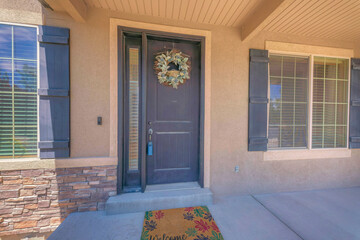 Black front door with lockbox, wreath, and side panel