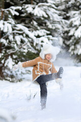 A girl in a funny fur hat and sheepskin coat is playing in a snowy forest