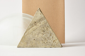 concrete tile in the shape of a triangle, beige corrugated cardboard and a glass arch on a light...