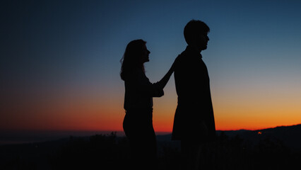 Silhouette of boy and girl hug each other at sunset