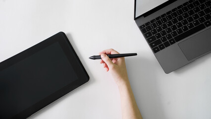 Female hand and stylus next to graphic tablet and laptop. White background. The concept of modern technological creativity