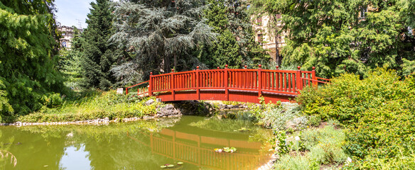 Zagreb, Croatia - August 2021. Idyllic Japanese bridge over the lake in the summer green botanical...