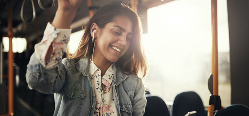 Smiling young woman riding on a bus listening to music