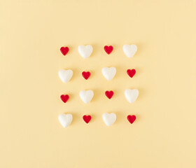 Creative idea made of white hearts and red gummy  candies on pastel yellow background. MInimal Valentines day or spring concept. Top view, flat lay.