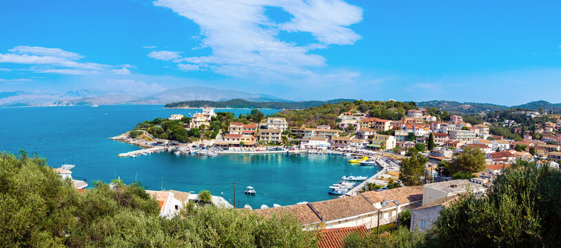 Panorama of Kassiopi town on Corfu island, Greece. Picturesque fishing village on rugged seashore with colorful houses, luxury villas and turquoise water. Popular tourist destination © Julia Lavrinenko