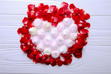 Heart of candy on a wooden background. Meringue heart. Decorated with rose petals