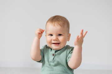 closeup portrait of a smiling baby in a green cotton bodysuit. products for children, early...
