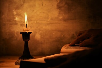 person with candle light reading