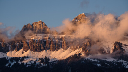 Bergkette von Wolken umgeben wird von der Sonne angeschienen. Ein nebulöses, eindrückliches Bild.
