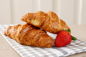 Two french croissants and a strawberry.