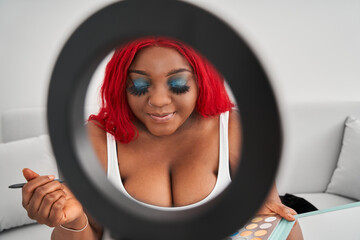 Multiracial redhaired girl closed eyes with bright eyeshadows and showing her make up to subscribers